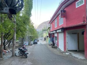 a street with a red building and a motorcycle parked on the road at Moon Light Guest House Khaplu in Khaplu
