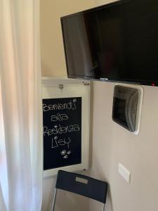 a chalk board with a tv on a wall at Residenza Lisy Rooms Affittacamere in Verbania +17 photos