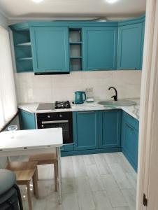 una cocina con armarios azules y fregadero en Апартаменты рядом с морем, en Sukhumi