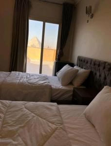 two beds in a hotel room with a view of the pyramids at king ramses pyramids view apartment in Cairo
