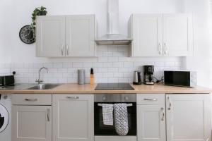 a kitchen with white cabinets and a stove top oven at Direct Prices, Spacious Apartment, Free Parking, Central Location Near To Uni, Hospital, Town in Exeter