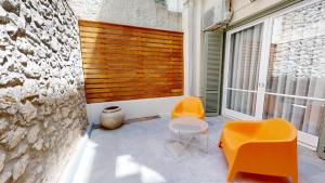 a room with two orange chairs and a wall at The Gate by Zoia Living in Athens
