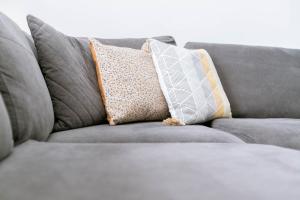 un sofá gris con almohadas encima en Direct Prices, Spacious Apartment, Free Parking, Central Location Near To Uni, Hospital, Town en Exeter