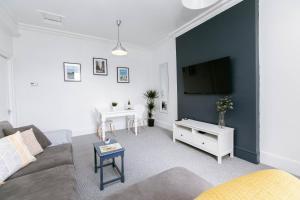 uma sala de estar com um sofá e uma televisão de ecrã plano em Direct Prices, Spacious Apartment, Free Parking, Central Location Near To Uni, Hospital, Town em Exeter