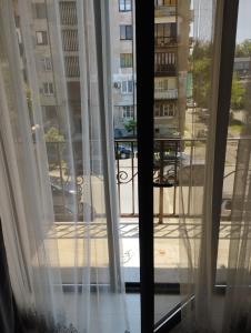 uma janela com cortinas brancas e vista para uma rua em Апартаменты рядом с морем em Sukhumi