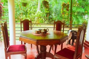 a dining room table and chairs with a dog standing around it at Canal Side Safari Resort in Udawalawe