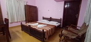 a bedroom with a large bed and a chair at VARMA SEA VIEW VILLAS in Trivandrum
