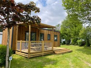 Cabaña de madera con terraza en un patio en Camping Haliotis, en Pontorson