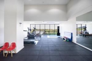 um ginásio com equipamento cardiovascular e cadeiras vermelhas em Lux 2 Bed 2 Bath Apartment in the Heart of Dickson, Canberra em Camberra
