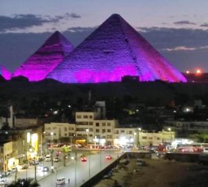 a view of the pyramids at night with purple lights at king ramses pyramids view apartment in Cairo