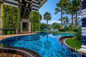 a swimming pool in a resort with palm trees at The Riviera Jomtien Brand new 1 Bedroom in Jomtien Beach