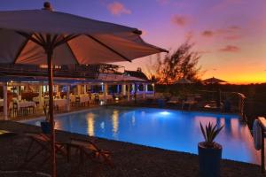 a swimming pool with an umbrella and chairs and tables at Le Grand Bleu in Andilana