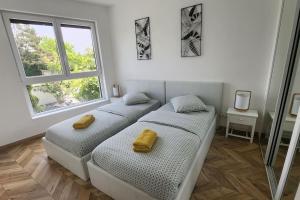 two beds in a white room with two windows at AOG PRESTIGE logement neuf avec SPA et écran de cinéma en rez de jardin in Colmar
