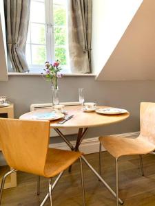 a table with two chairs and a vase of flowers on it at Scholar's Loft - Cosy & Close to Central Cambridge in Cambridge