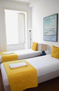 een hotelkamer met 2 bedden en gele dekens bij The Residences at Bairro Alto in Lissabon