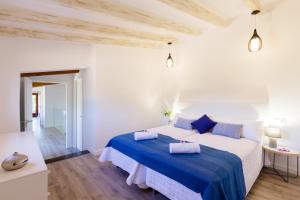 a white bedroom with a large bed with blue sheets at Can Tortet in Pollença