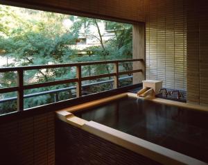 a bath tub in a room with a large window at Ryokan Sumiya Kihoan in Kameoka