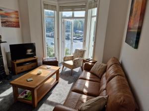 a living room with a brown couch and a table at Looe Spacious 4 Double bedroom House Sleeps 9 Harbour River Views in Looe