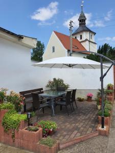 een tafel en stoelen onder een paraplu voor een kerk bij Ferienwohnung am See in Regis-Breitingen
