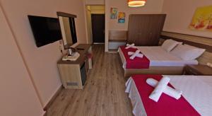 a small hotel room with two beds and a tv at Eden Pyara Hotel Turunc in Turunc