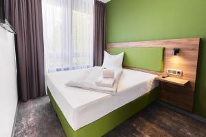 a small bedroom with a bed with a green wall at Hotel Rhönkitz in Bad Kissingen