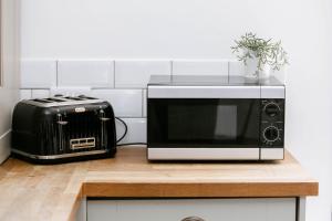 a microwave and a toaster oven on a kitchen counter at Peaceful Apartment - Dedicated Free Parking - Walk to Centre, Uni, Hosp - Business and Leisure - Contact For Long Stays in Exeter