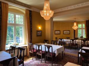 a dining room with tables and chairs and a chandelier at Hotel Kronprinz in Falkensee