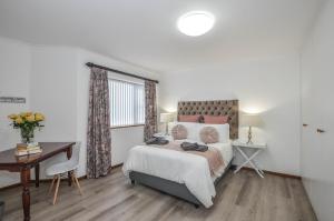 a bedroom with a bed and a desk and a window at Wees Gerus in Yzerfontein