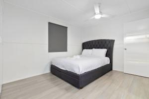 Schlafzimmer mit einem Bett mit einem schwarzen Kopfteil in der Unterkunft Moreton Views! in Beachmere