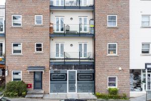 ein Backsteingebäude mit Fenstern und einem Balkon in der Unterkunft Velvet 2-bedroom apartment, Conduit Lane, Hoddesdon in Hoddesdon