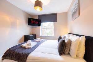 a bedroom with a bed with a tv on the wall at Velvet 2-bedroom apartment, Conduit Lane, Hoddesdon in Hoddesdon