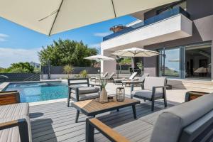 un patio con mesa, sillas y piscina en Villa Dekorti - Adriatic Luxury Villas, en Kožino