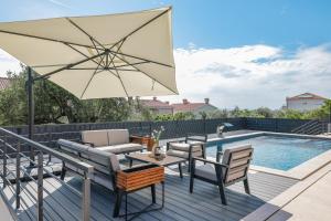 un patio con sombrilla y sillas junto a una piscina en Villa Dekorti - Adriatic Luxury Villas, en Kožino