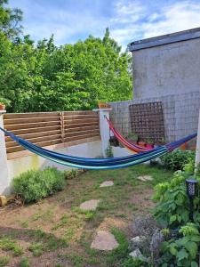 eine Hängematte in einem Garten neben einem Zaun in der Unterkunft Magnifique logement avec sauna infra rouge in Saint-Jean-de-Boiseau