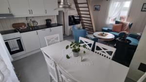 a kitchen and living room with a white table and chairs at Autentisk rorbu i burekka, Stamsund in Stamsund