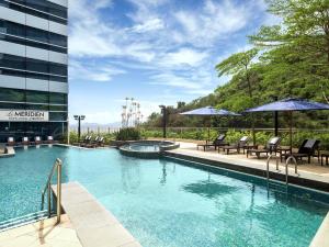 einen Pool mit Stühlen und Sonnenschirmen neben einem Gebäude in der Unterkunft Le Méridien Hong Kong, Cyberport in Hongkong