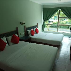 two beds with red pillows in a room with a window at Highway Inn in Mukah