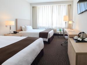 um quarto de hotel com duas camas e uma secretária em Spark Hoteles em Antofagasta