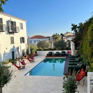 a swimming pool with lounge chairs and a building at Yayaki Spetses in Spetses