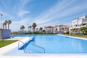 a large swimming pool with palm trees and buildings at Las Terrazas Primera Línea de playa in Mezquitilla