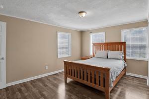 a bedroom with a wooden bed and two windows at Pleasant Hill Home in Wooddale