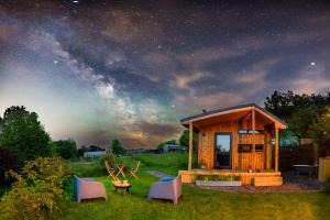 Cabaña de madera pequeña con sillas y mesa en un campo en Luxury Glamping Cabin with Outdoor Bath on Cornish Flower Farm, en Truro