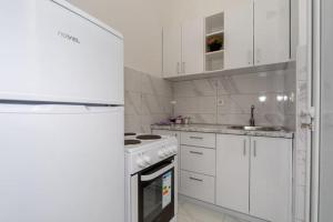 a kitchen with white cabinets and a stove top oven at Apartmani Bar in Bar
