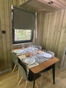 a table with plates and glasses on it in a room at Szopa_Narie in Gulbity
