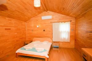 1 dormitorio con 1 cama en una habitación de madera en Sunrise Bungalows, en Cıralı