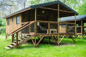 a large wooden cabin with a porch and a play house at Camping Le Mouliat in Moncrabeau