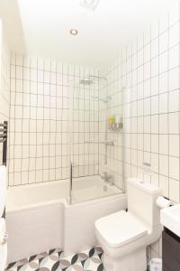 a white bathroom with a tub and a toilet at Sunbeam and Sundance Cosy House in Whitstable