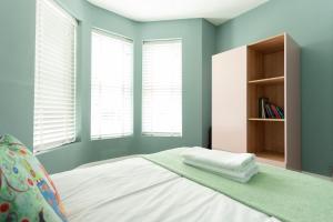 um quarto com paredes azuis e uma cama com uma estante de livros em Sunbeam and Sundance Cosy House em Whitstable