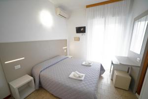 una camera da letto con un letto e due asciugamani di Hotel Ischia a Rimini