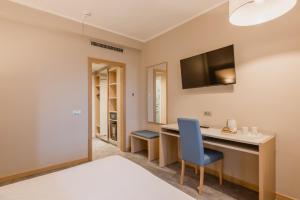 a bedroom with a desk and a tv on the wall at Hotel Calabona in Alghero